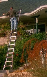 Using ladder to clean gutters